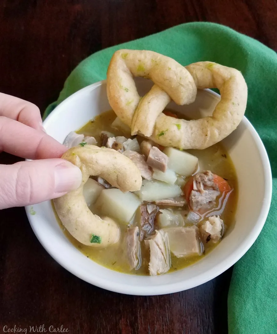 dipping celtic knot roll into bowl of easy chicken stew.