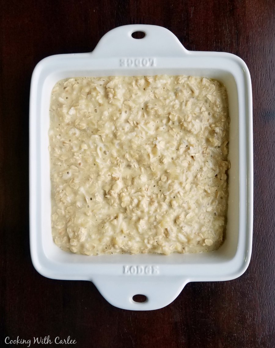 Square baking dish with pineapple and coconut baked oats batter inside, ready to go in the oven. 