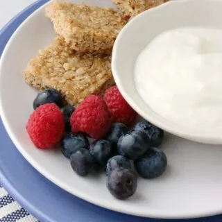 breakfast with berries, yogurt and oatmeal bars.