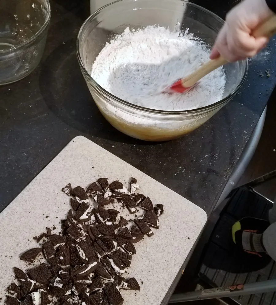 stirring together blondie batter with spatula, cutting board of chopped oreos nearby.