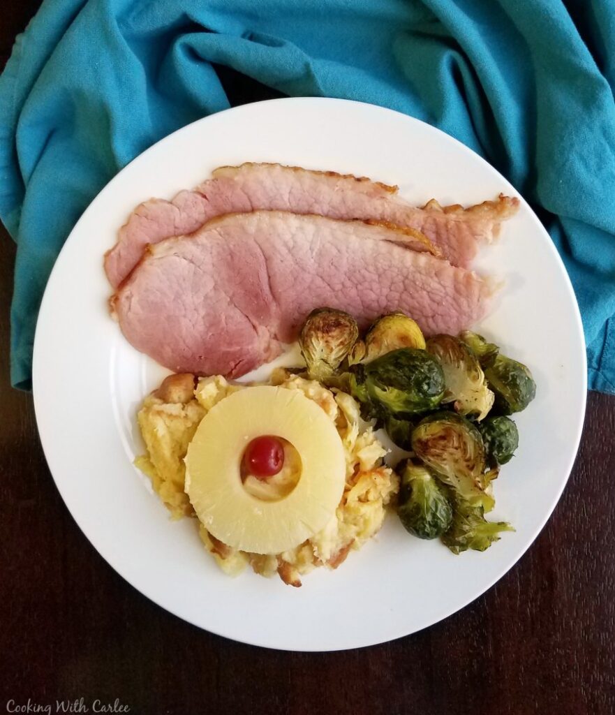 plate loaded with ham, brussels sprouts and pineapple casserole.