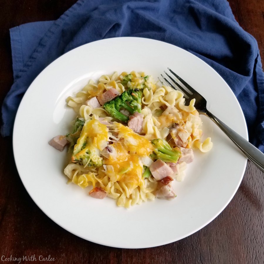 Plate of cheesy pasta casserole with ham and broccoli, ready to eat.