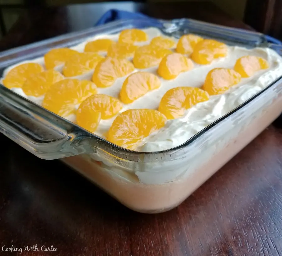 pan of creamy orange jello topped with fluffy vanilla pudding topping and orange slices