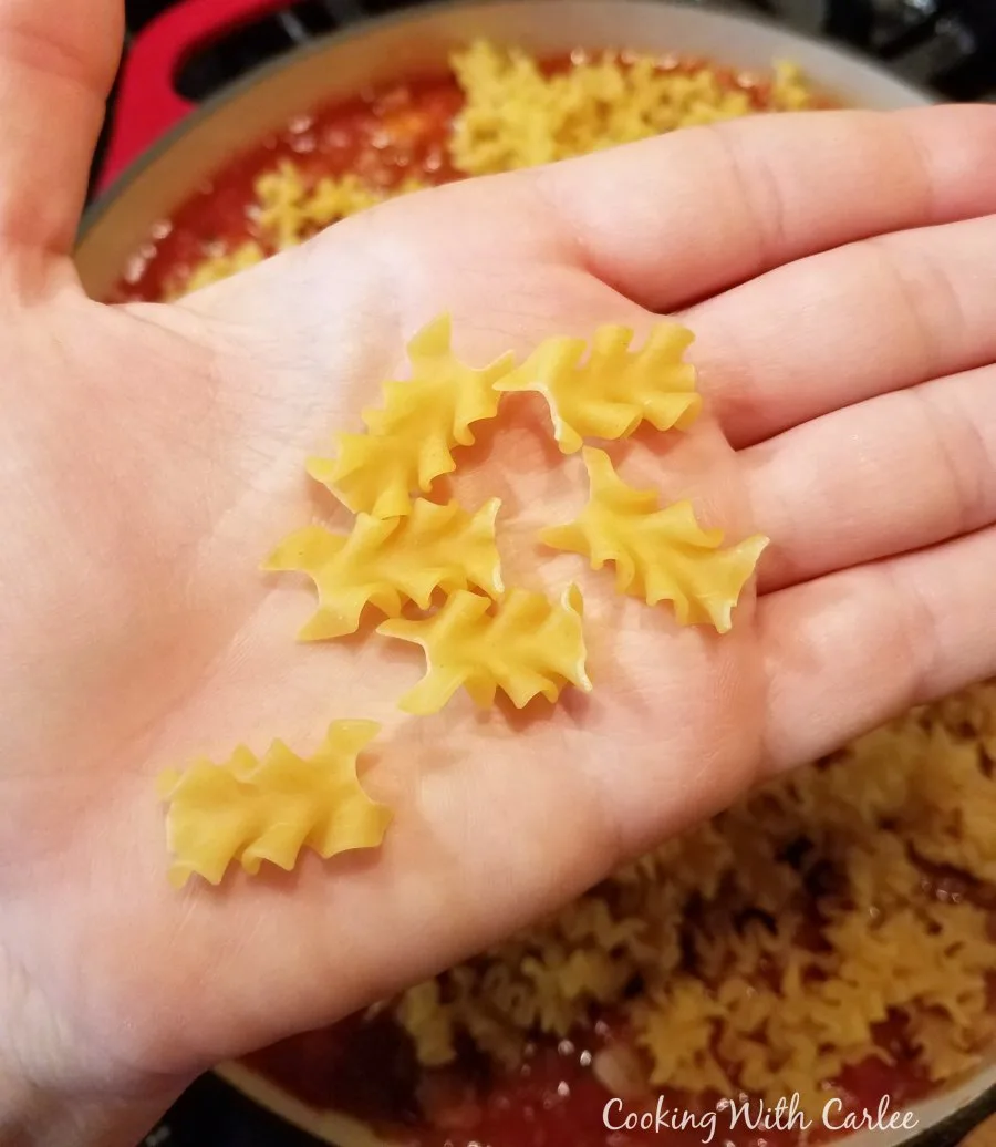 close up of mafalada pasta in hand, looks like mini lasagna noodles.