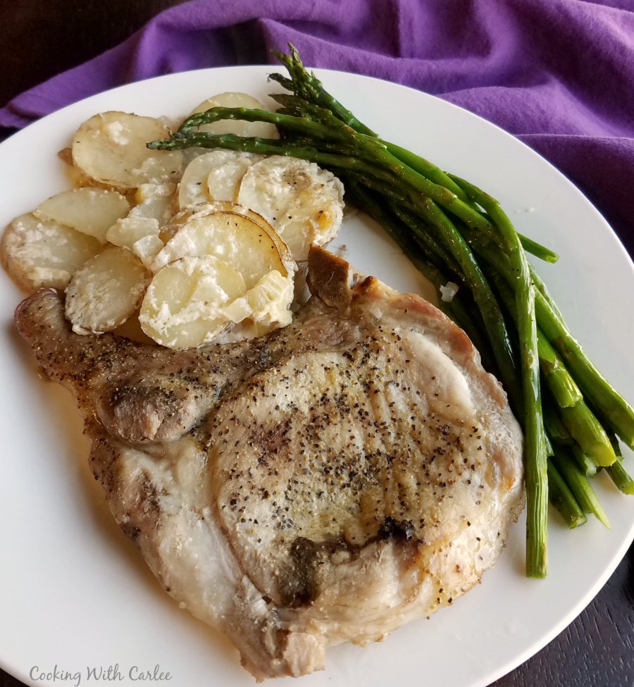 dinner plate with pork chop, potatoes and asparagus.