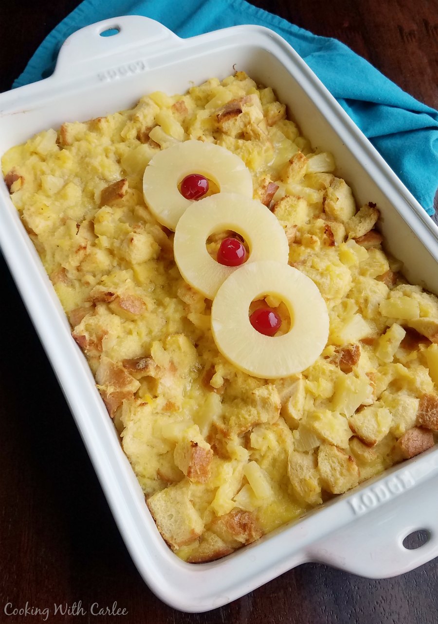 Casserole dish filled with baked scalloped pineapple, topped with three pineapple rings and maraschino cherries.