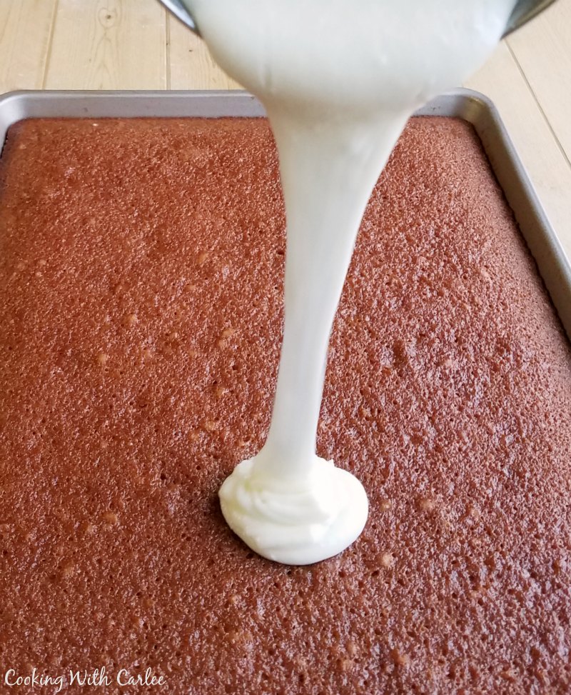 pouring white icing over cherry cake.