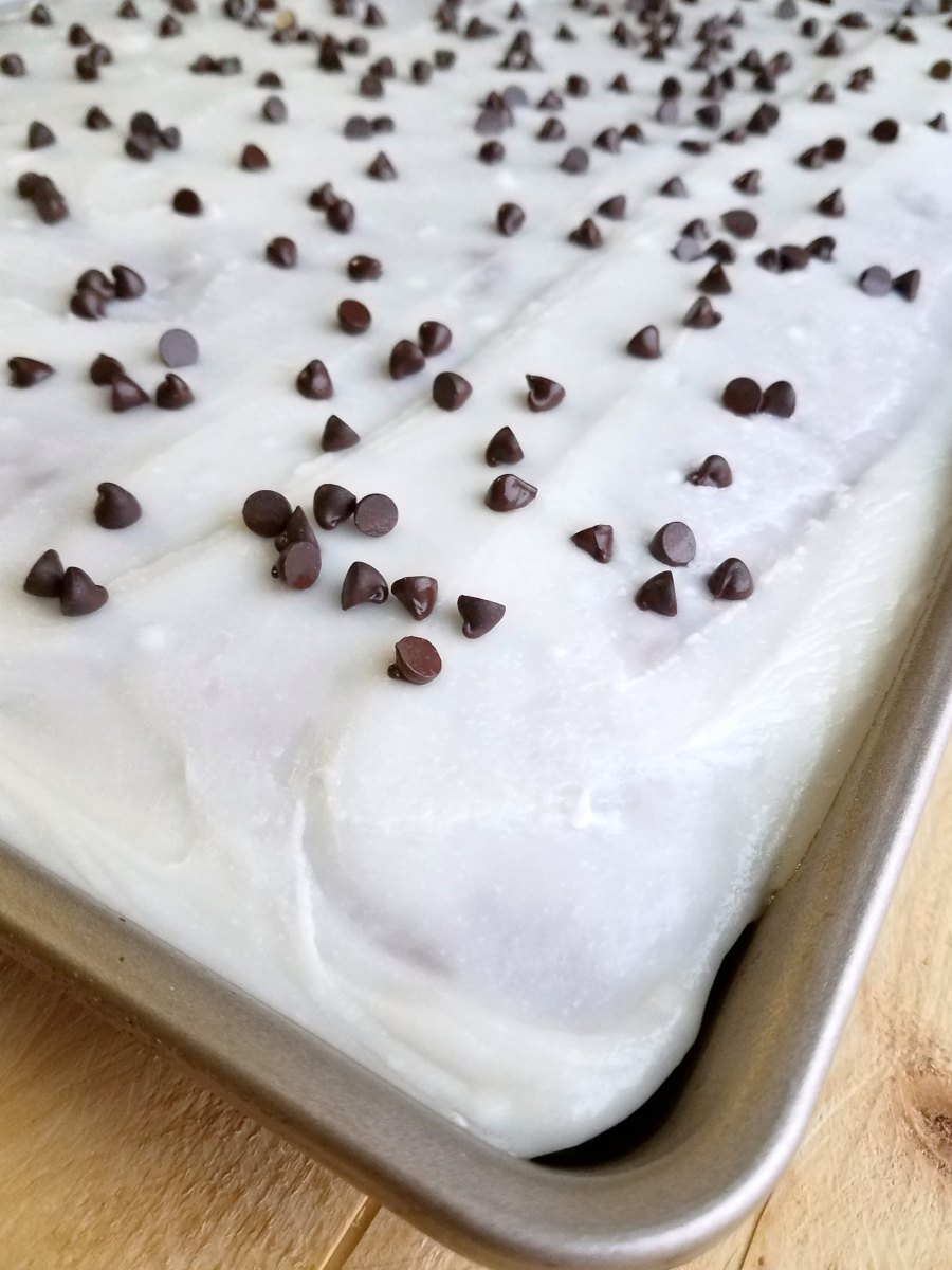 corner of sheet cake with icing and chocolate chips.