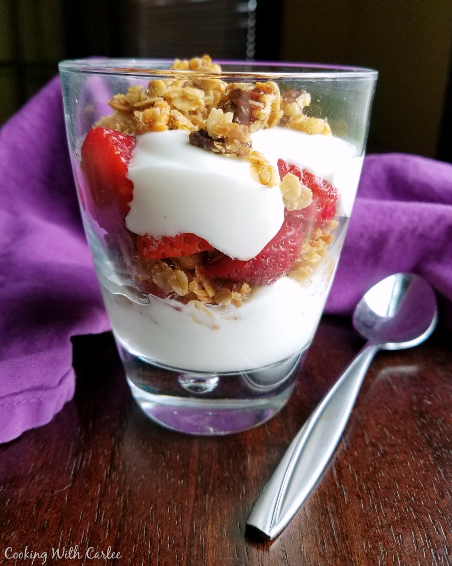 glass filled with layers of yogurt, granola and strawberries