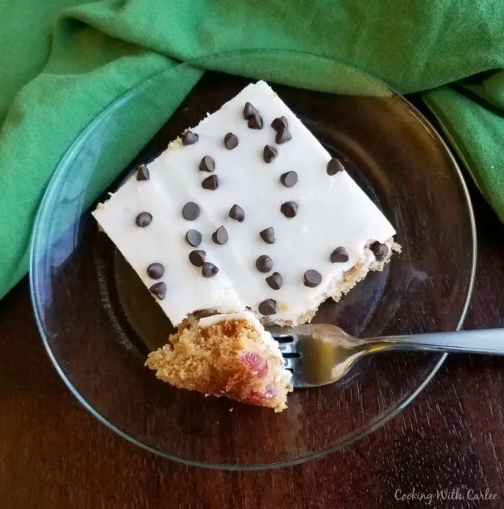 piece of cherry chocolate chip Texas sheet cake with white icing and chocolate chips on top.