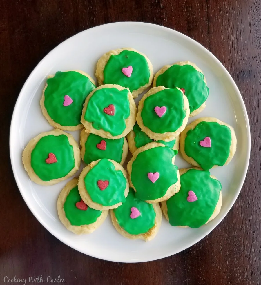 Sour cream cookies with green icing and candy hearts on top for Grinch cookies. 