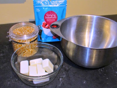 bowl of white chocolate, bag of freeze dried strawberries and container of popcorn next to big bowl