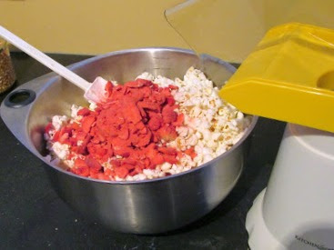 stirring crushed strawberries into popcorn mixture