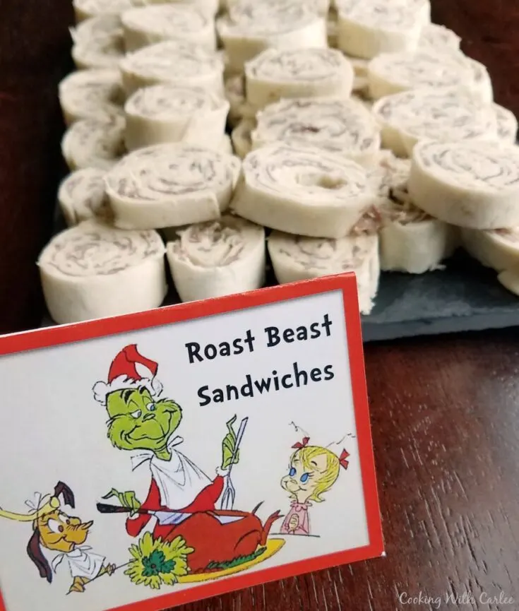sign with The Grinch on it that say Roast Beast Sandwiches in front of pile of pinwheels.