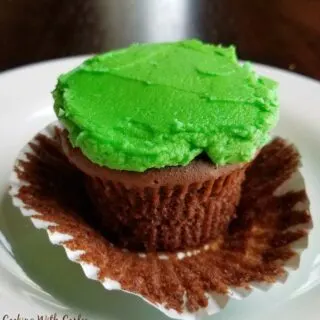 chocolate cupcake with wrapper pulled down and green frosting on top.