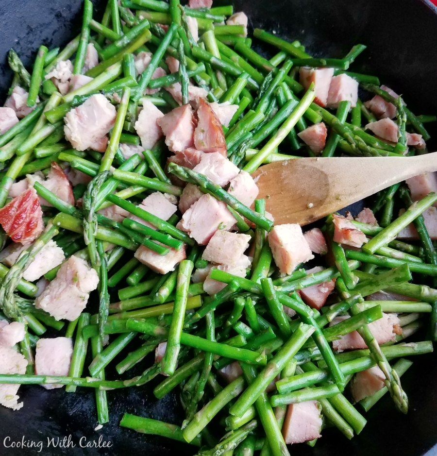 bits of ham and asparagus cooking in cast iron skillet.