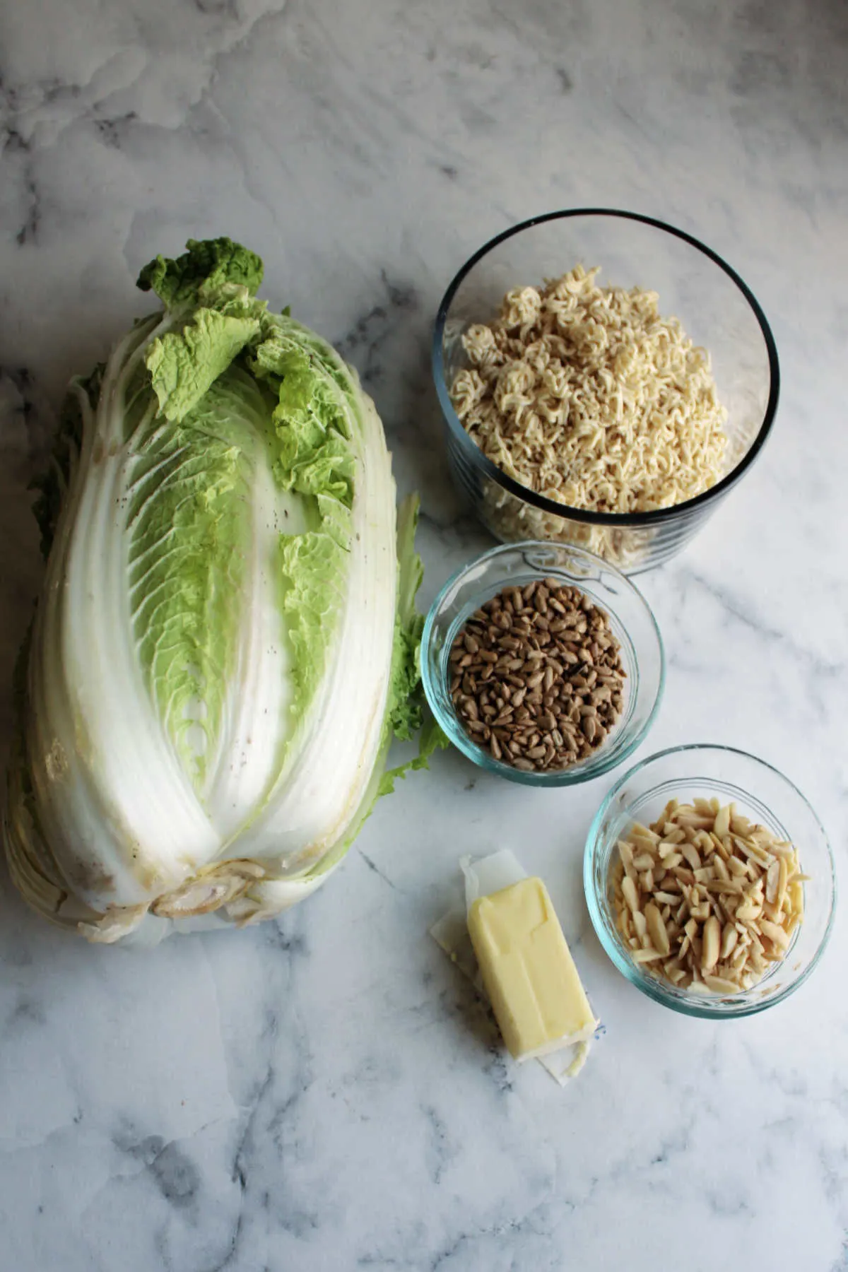 Napa cabbage, ramen noodles, sunflower seeds, slivered almonds and butter ready to be made into salad.
