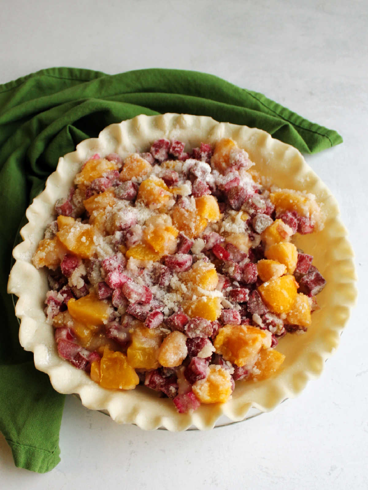 raw pie crust filled with peaches and rhubarb tossed in sugar and flour.