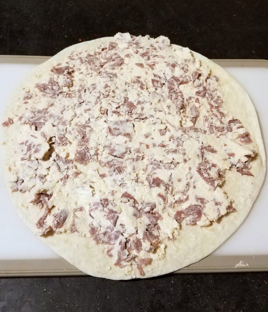 tortilla with cream cheese and beef mixture spread over it.
