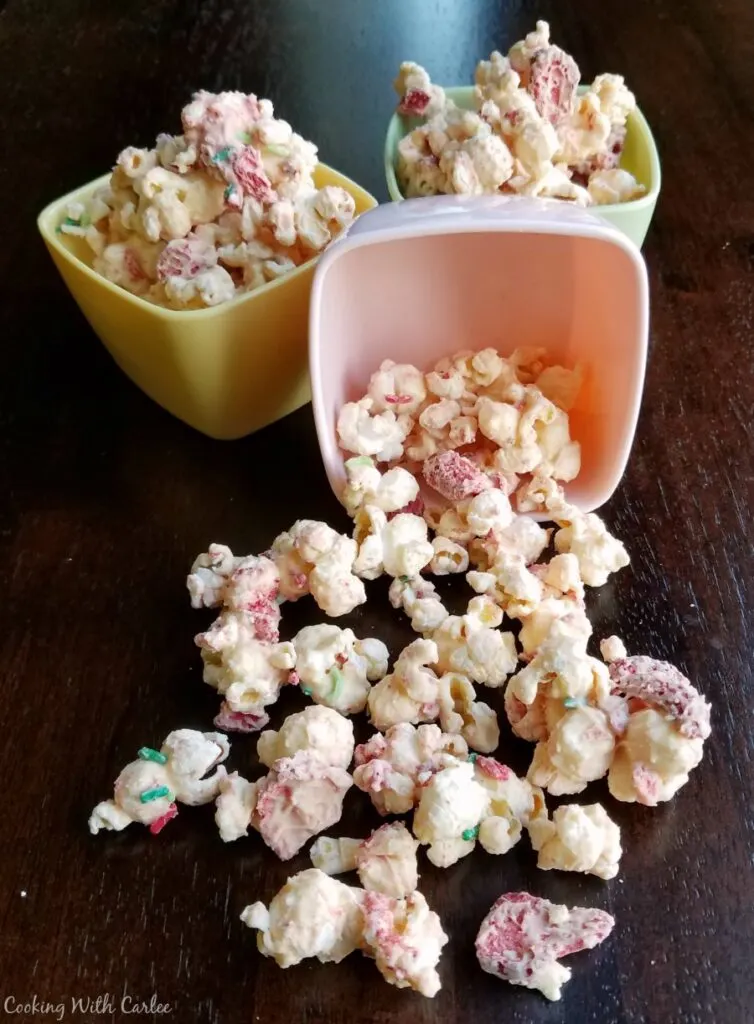 small bowls of strawberry and white chocolate popcorn spilled on counter.