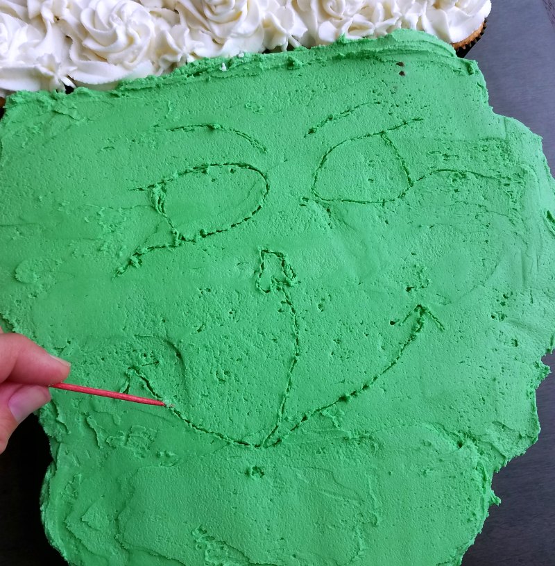 tracing grinch face into frosting with a toothpick before adding colored frosting.
