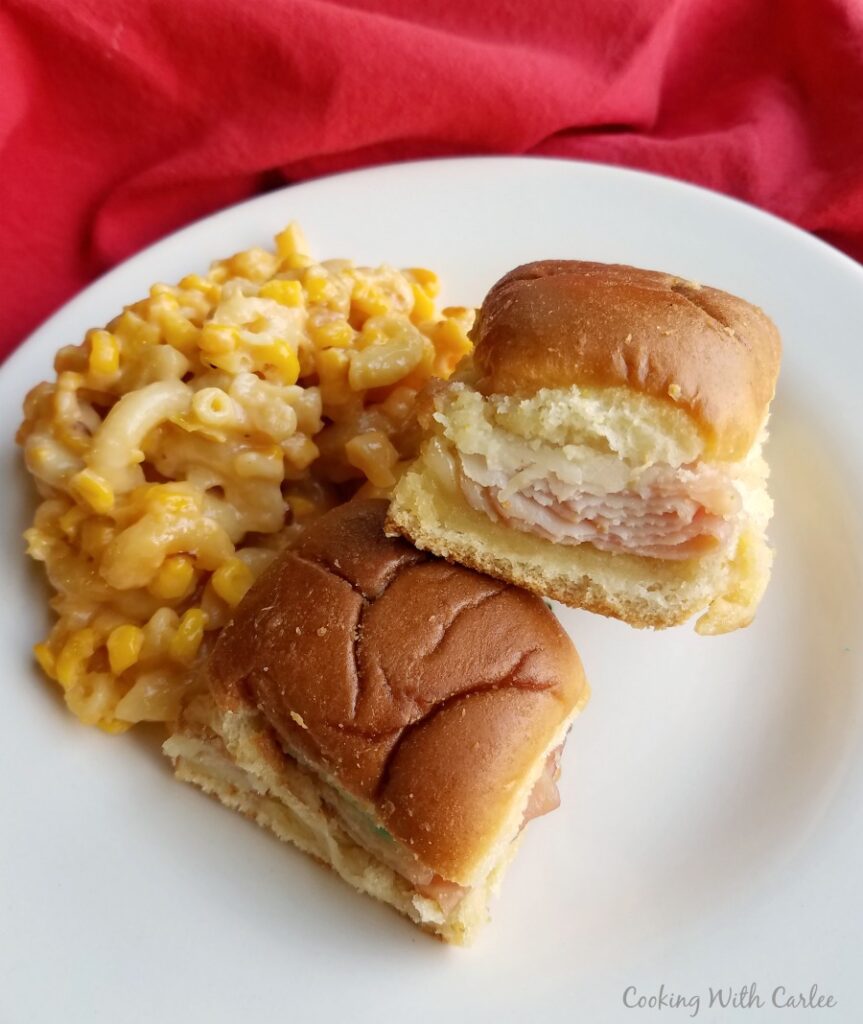 Hot turkey ham and cheese sliders served on plate with corny mac and cheese. 