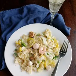 dinner plate of pasta primavera with a glass of white wine.