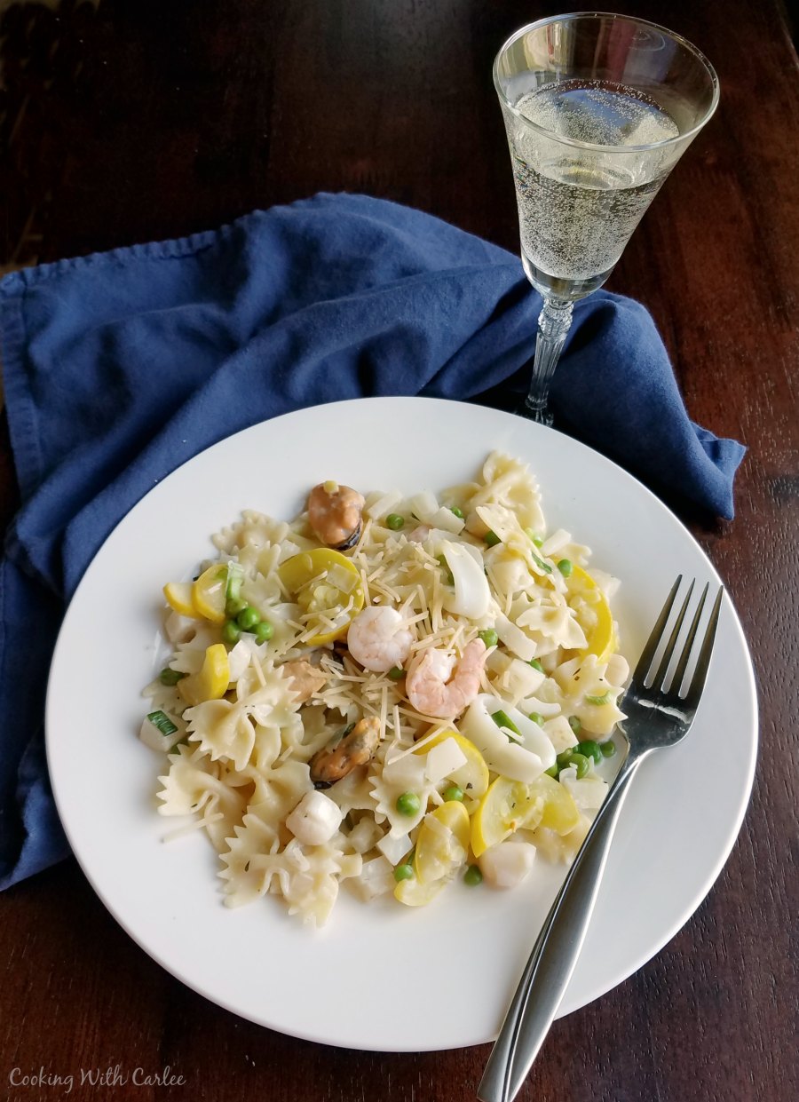 dinner plate of pasta primavera with a glass of white wine.