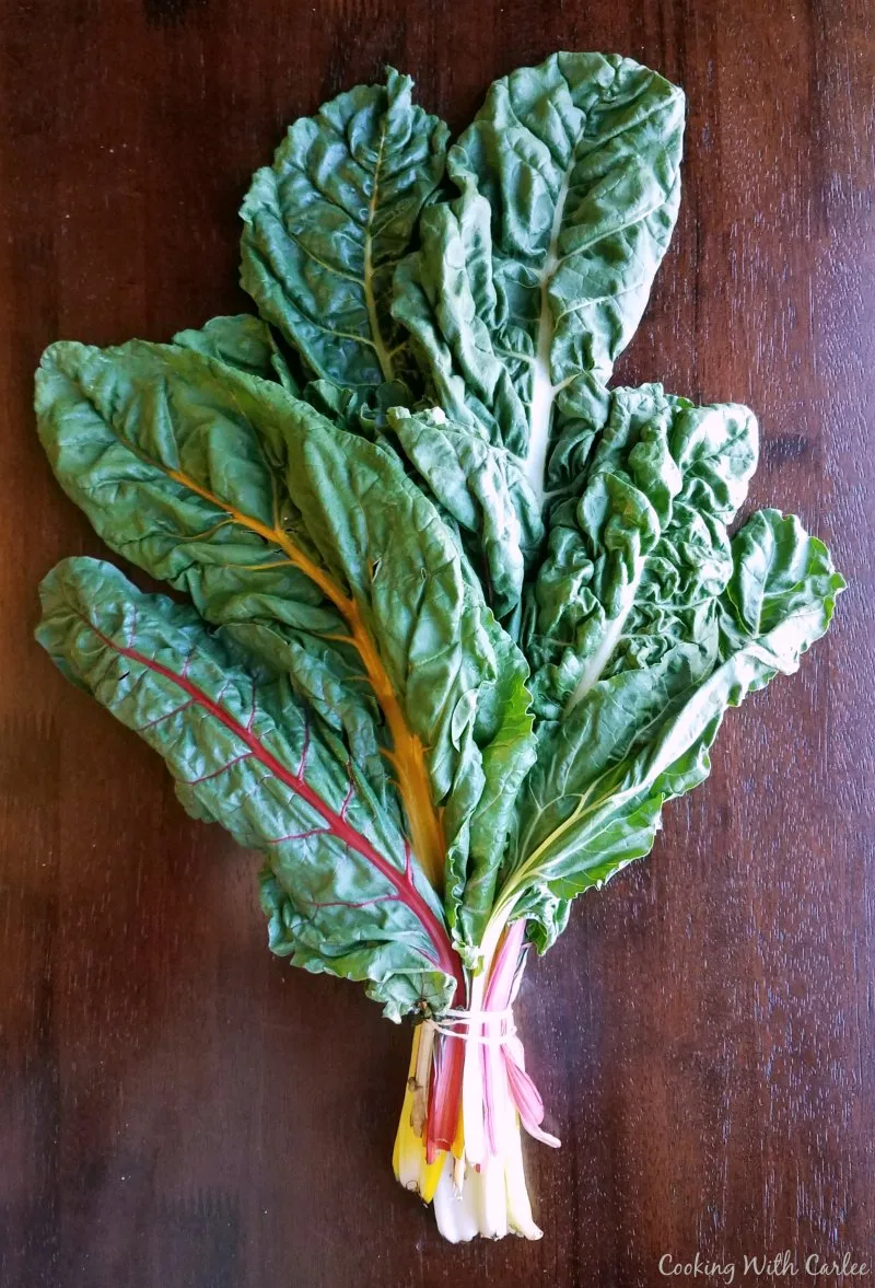 Bunch of rainbow chard with different colored stakes and green leaves. 