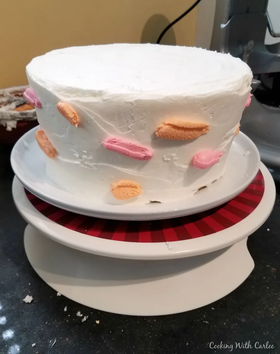 white iced "cake" with dots of orange and pink frosting randomly on it.
