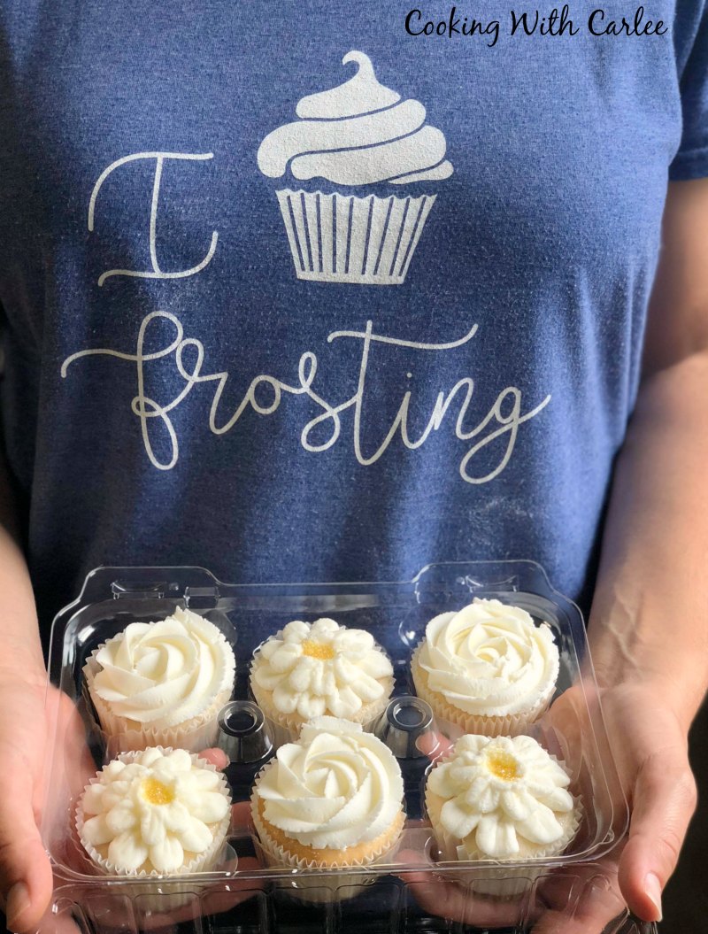 holding container of cupcakes frosted with perfect not too sweet buttercream wearing I cupcake frosting shirt
