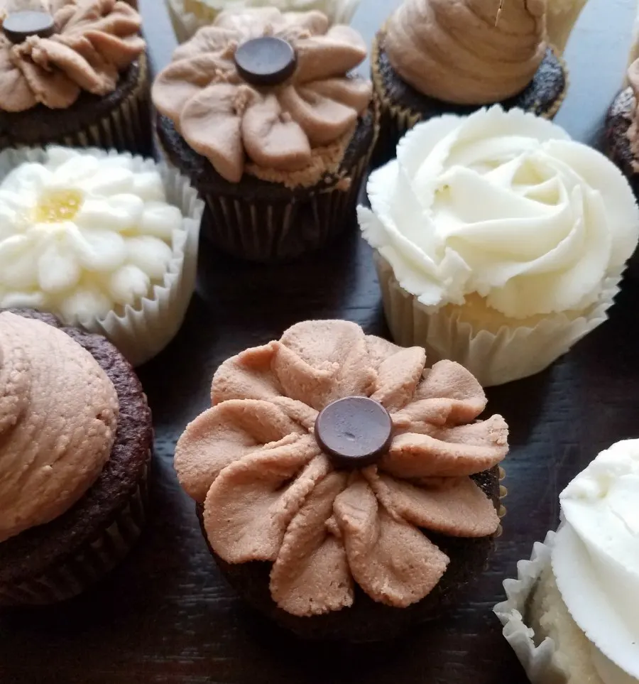 Cupcakes with chocolate flowers and white frosting flowers piped on top as rustic wedding desserts.