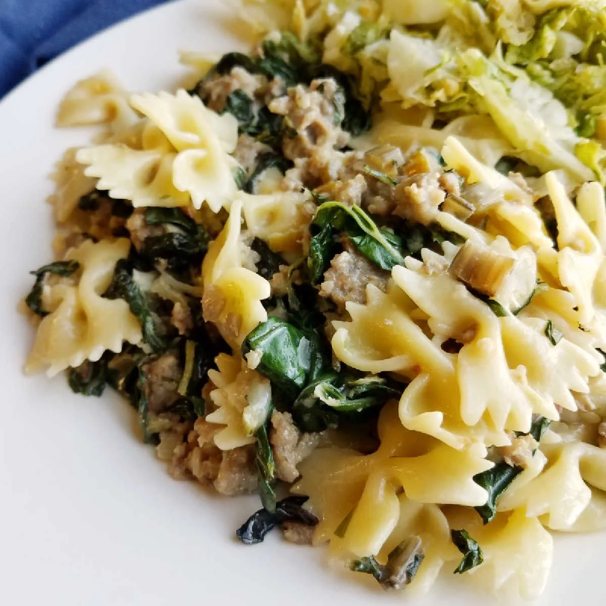 close up of serving of pasta with wilted greens and sausage.