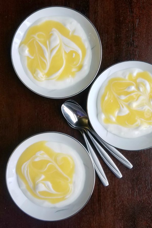 three small bowls of lemon curd and granola topped yogurt.