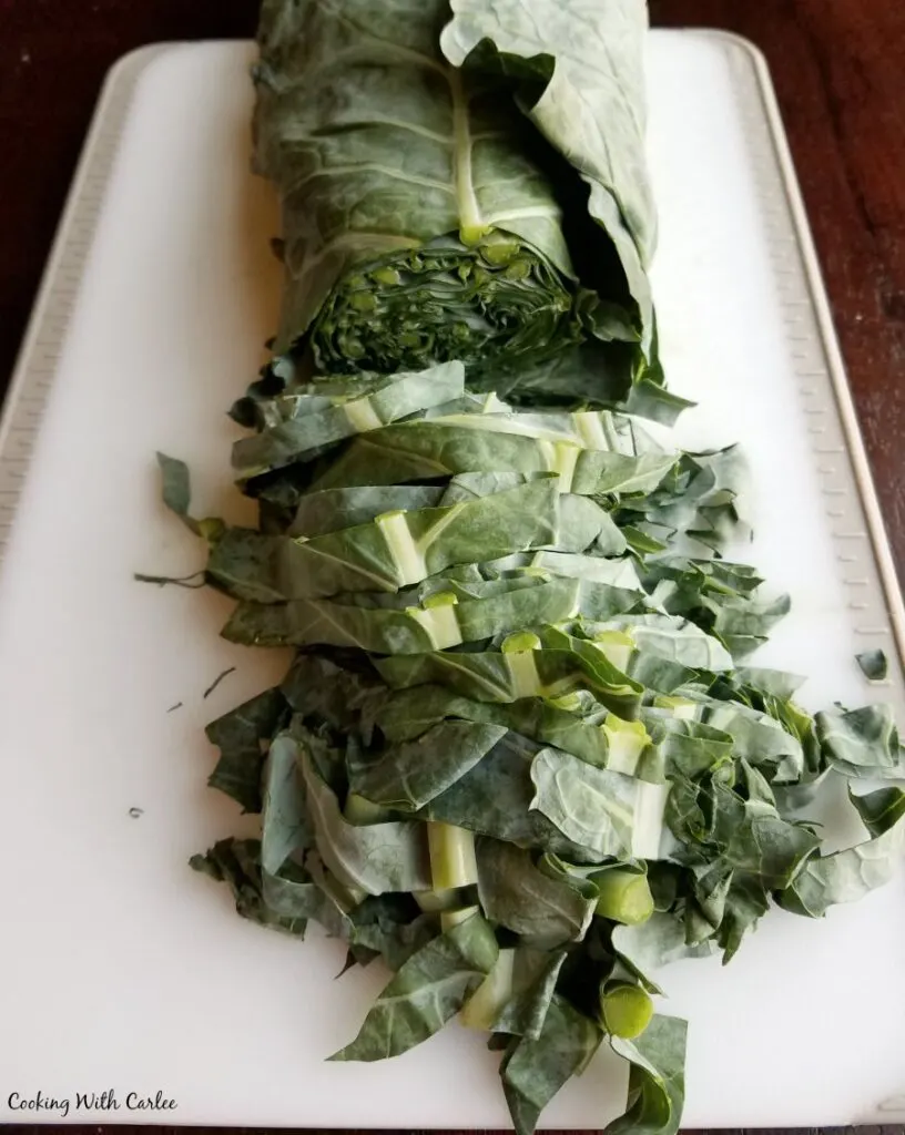 collards rolled up like a cigar and being sliced into small pieces.
