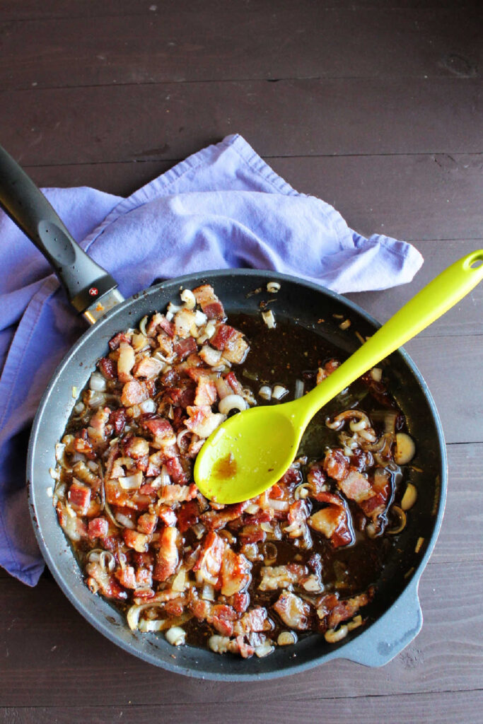 skillet full of warm bacon dressing with bits of onion and bacon in it.