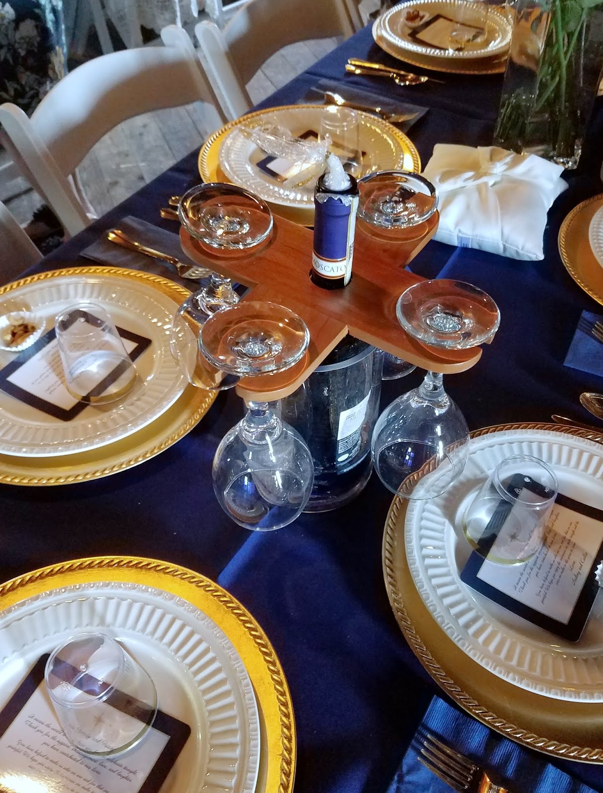 place settings on table with gold chargers and white bottle with homemade wooden wine glass holders.