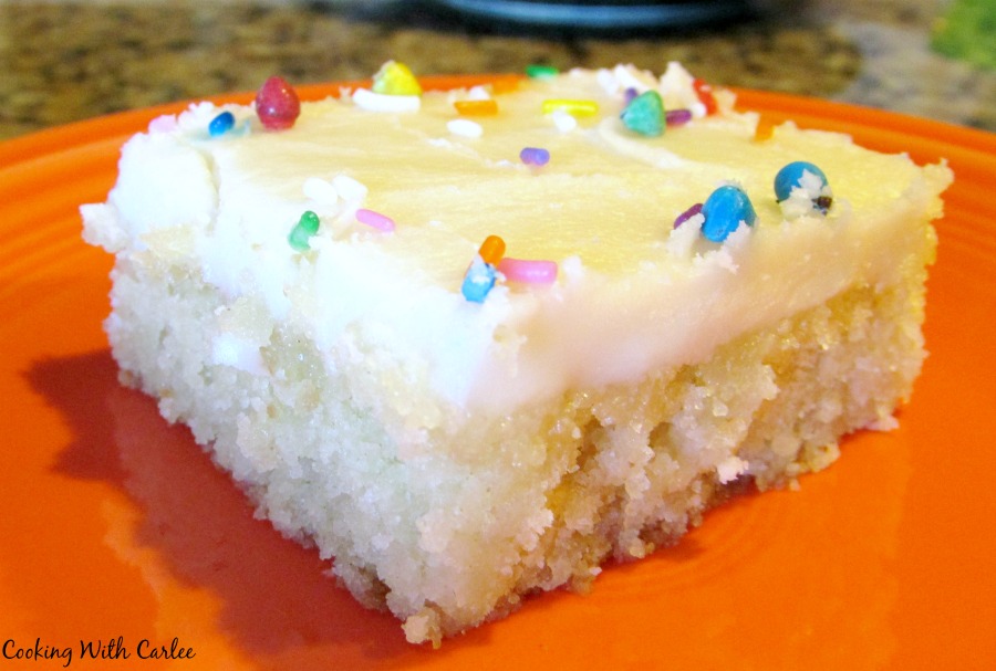 sprinkle topped piece of white texas sheet cake on orange plate.