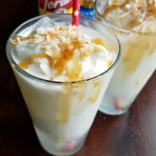 close up of whipped cream, coconut and caramel topped italian soda.