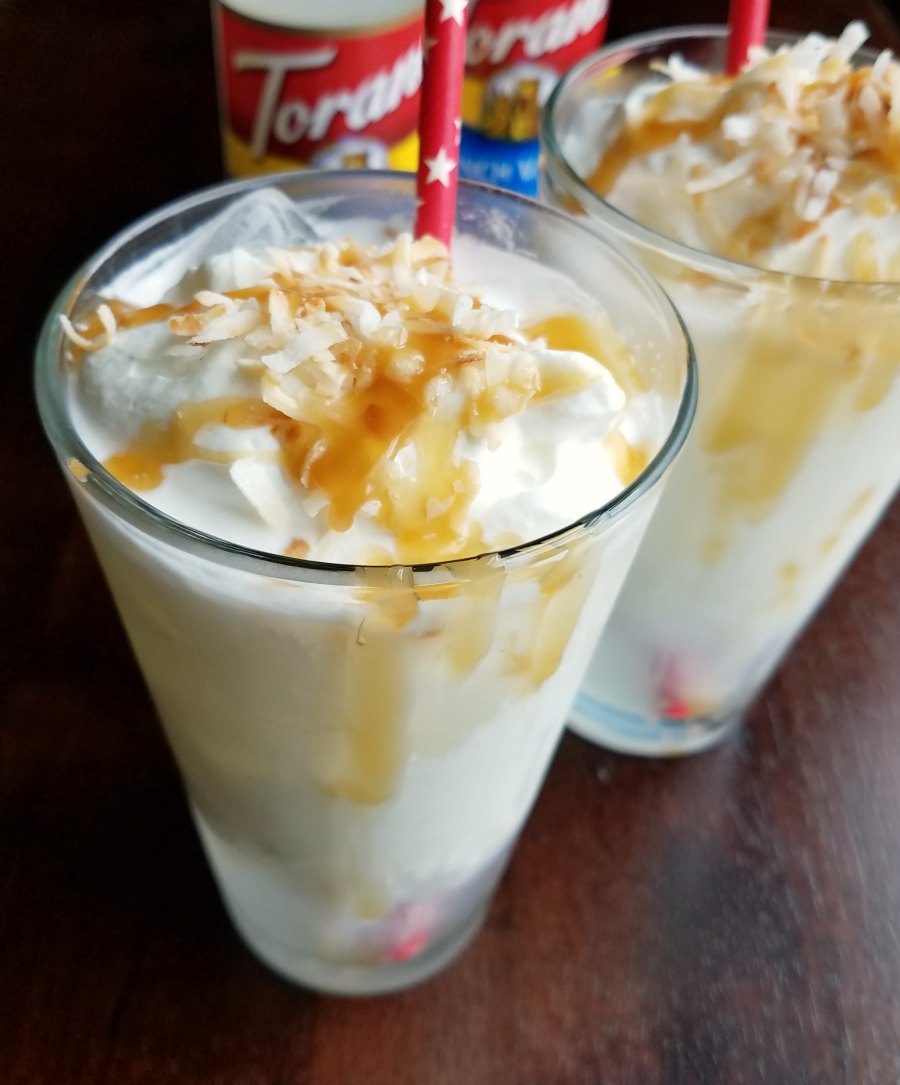 close up of whipped cream, coconut and caramel topped italian soda