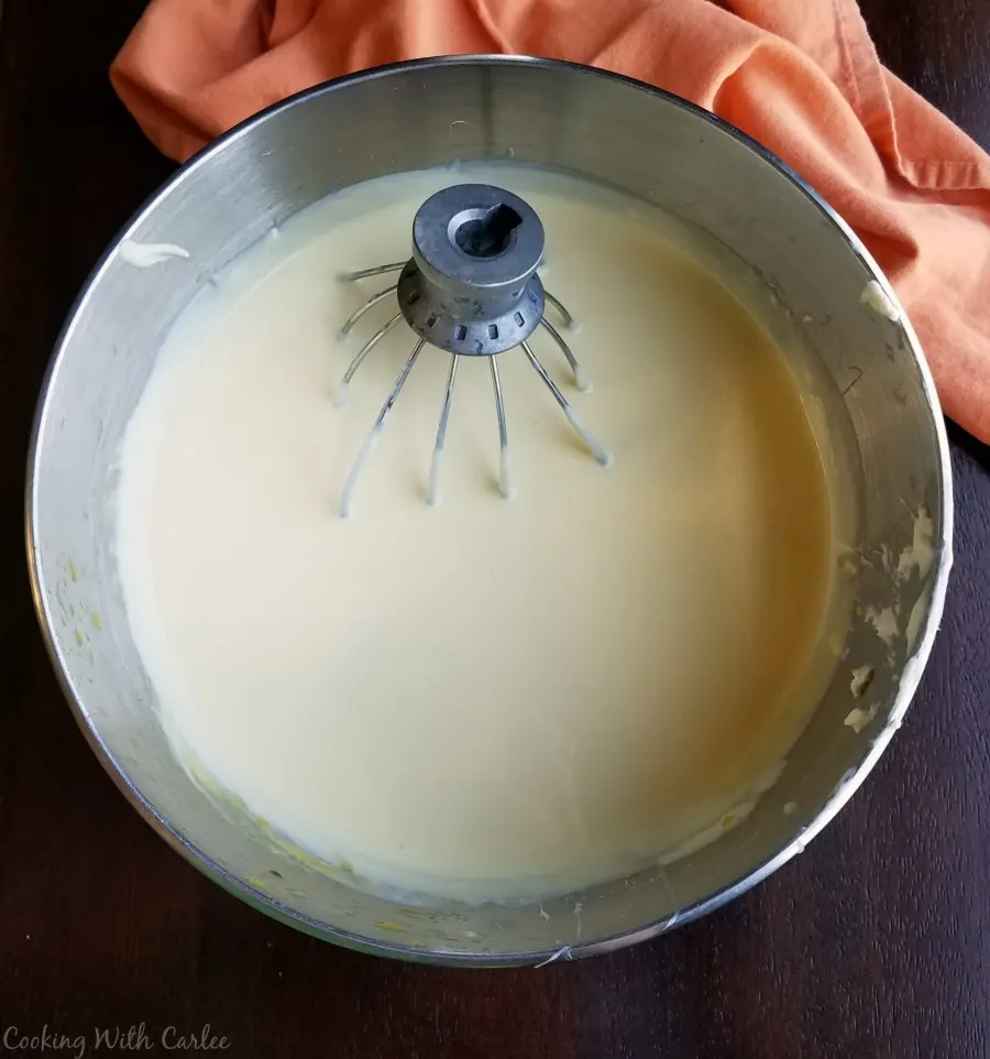 mixer bowl filled with orange cream cheese ice cream base.