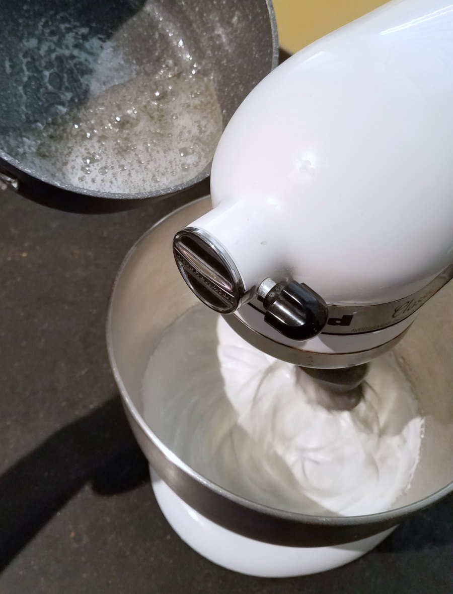 pouring hot sugar syrup into mixer that is beating egg whites.