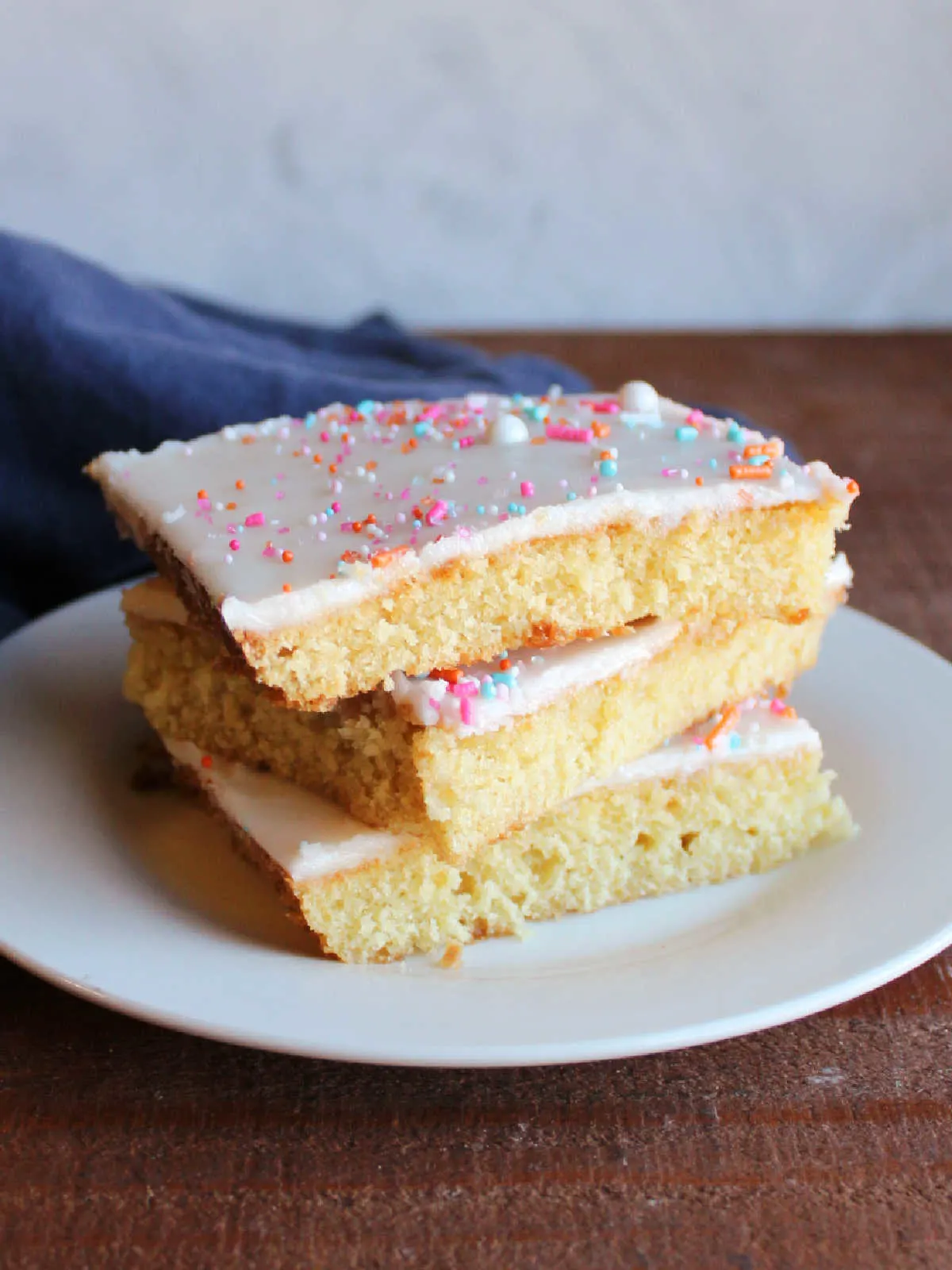 Stacked pieces of white Texas sheet cake with vanilla icing and sprinkles on top.