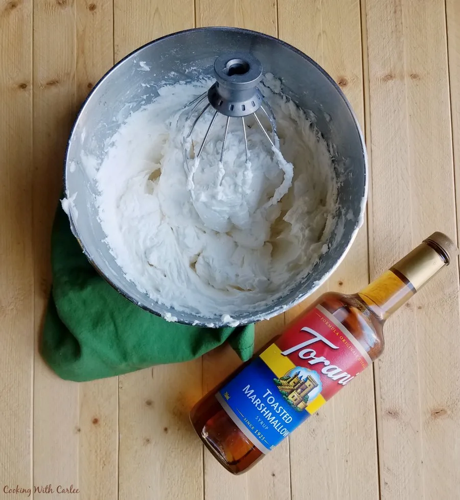 mixer bowl of whipped cream and a bottle of flavored syrup