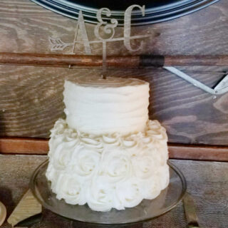 Two tier wedding cake with a 6 inch layer on top of an 8 inch layer with frosting and an initials topper.
