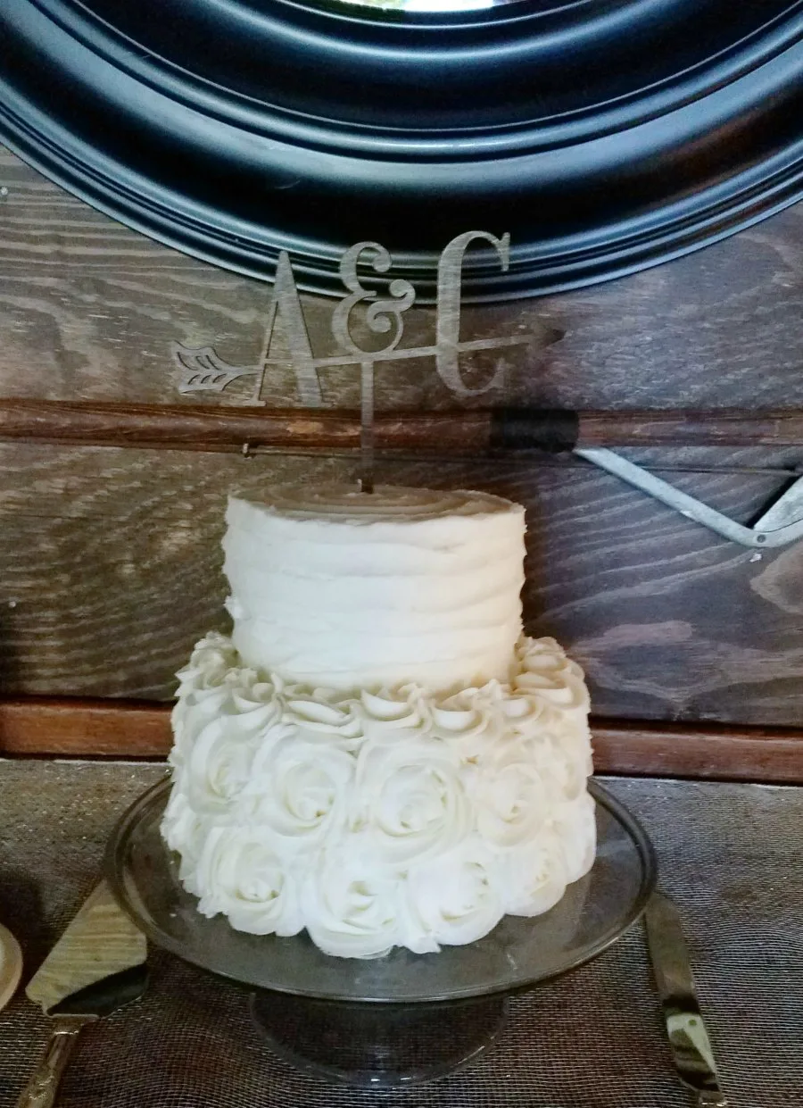 wedding cake with 1 large layer and 1 small layer. Rosettes on bottom and subtle ruffle on top layer in frosting