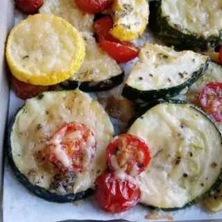 Parmesan roasted zucchini and cherry tomatoes fresh from the oven with melted cheese and seasonings on the cooked vegggies.