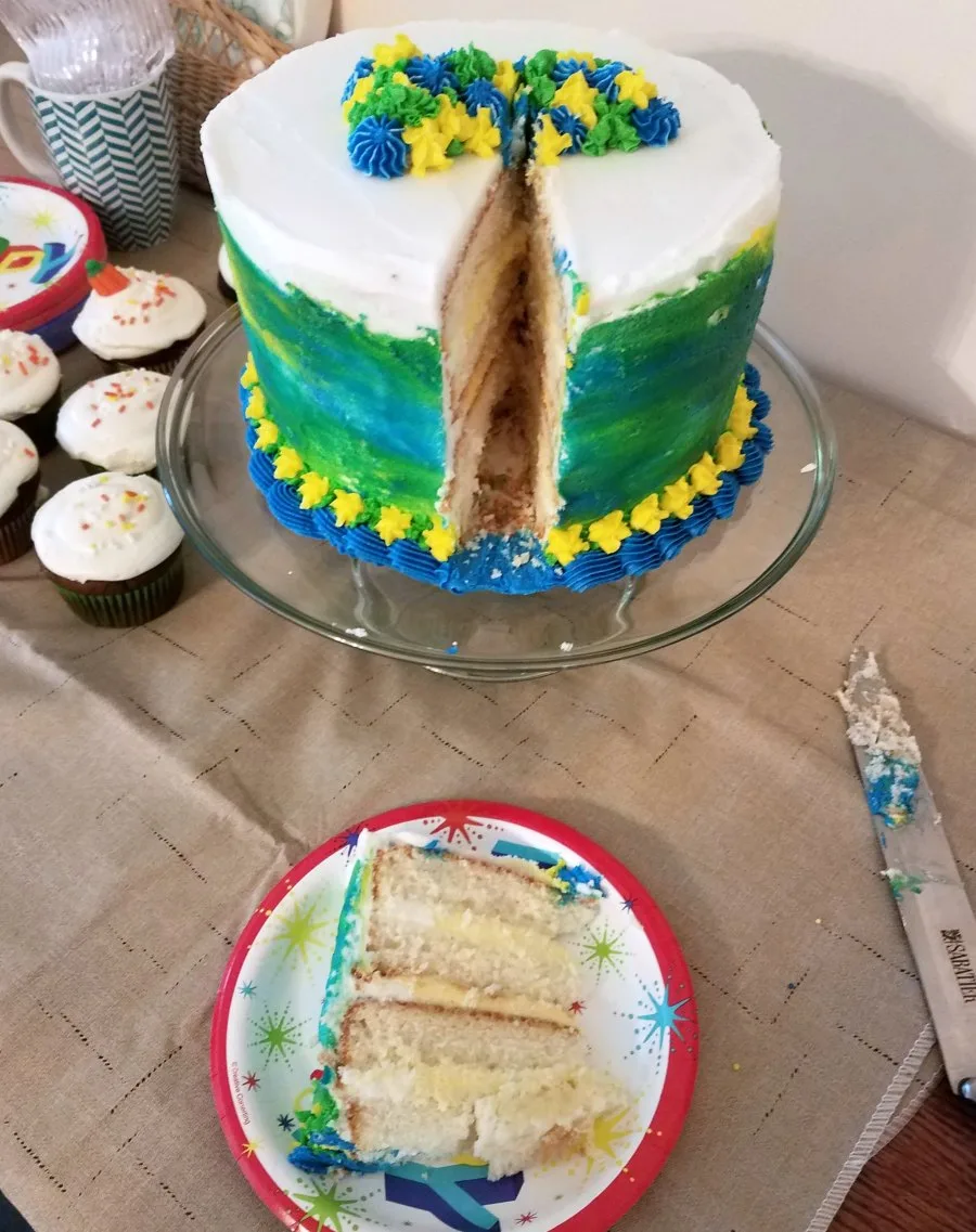 first slice of birthday cake served showing layers of white cake, buttercream, and pudding cake filling. 