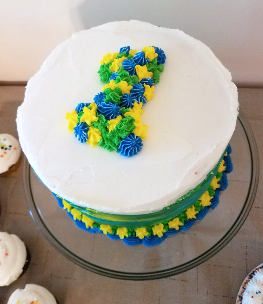 first birthday cake with blue yellow and green frosting number 1 on top