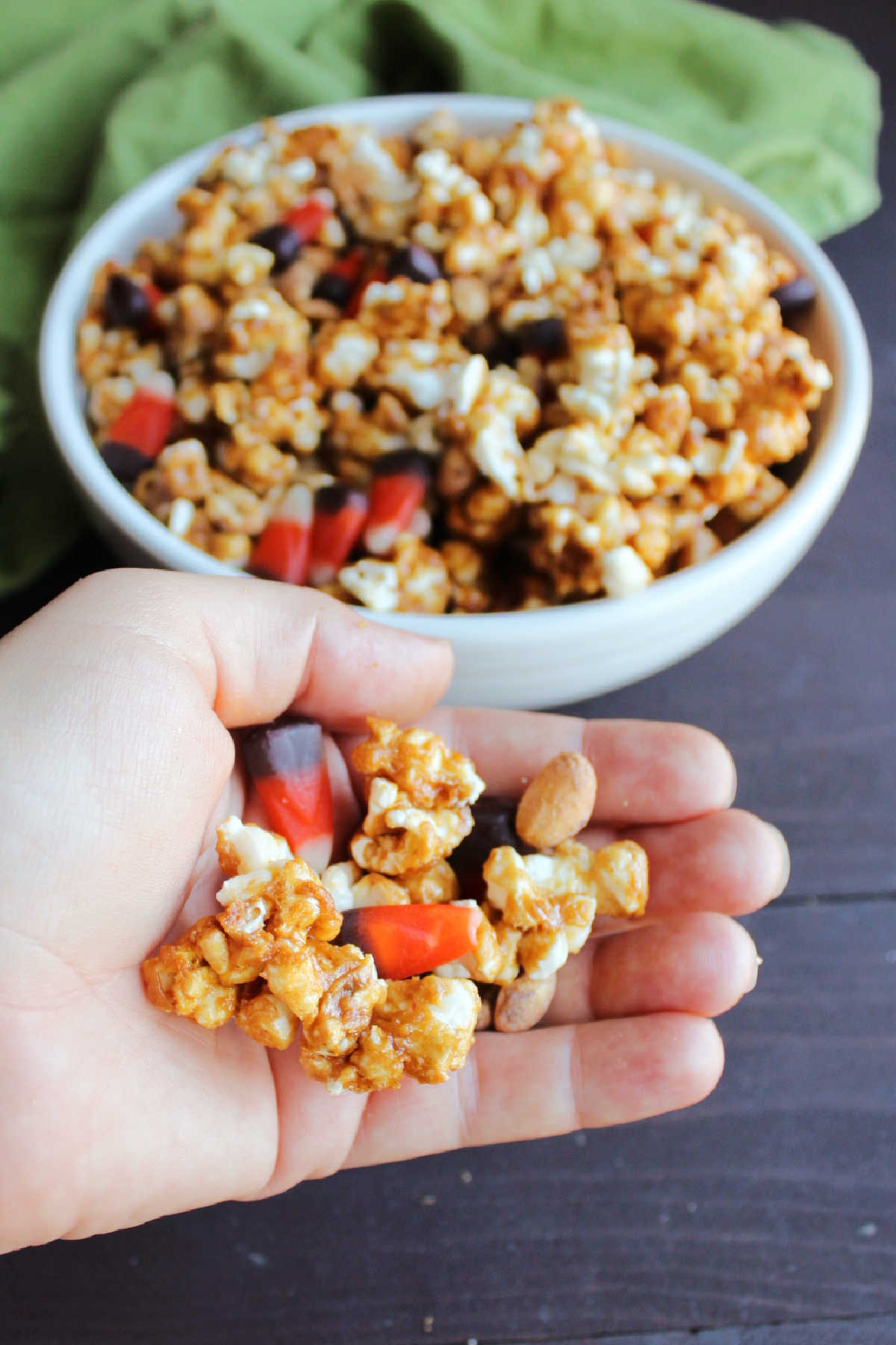 Hand filled with crunchy peanut butter popcorn, peanuts and candy corn ready to eat. 